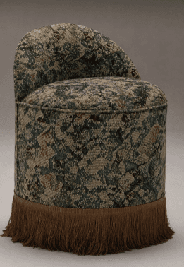 An upholstered round back chair or vanity stool featuring a distinctive multi-color patterned fabric. The chair has a curved backrest, a circular seat, and a cylindrical base, which is fully covered and adorned with a long, decorative fringe around its bottom edge. No legs are visible. — 3D model