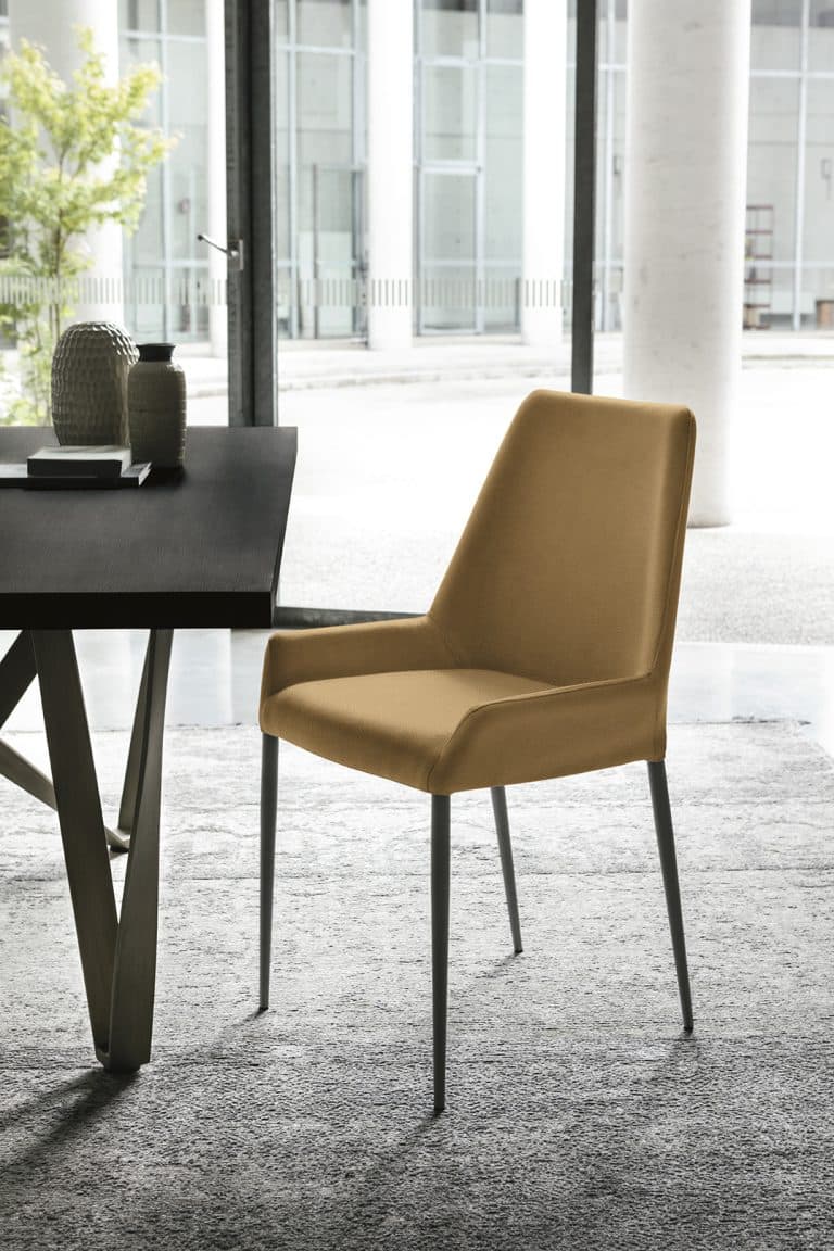 A contemporary dining chair featuring full mustard-yellow fabric upholstery and slender, tapered black metal legs, with integrated armrests. — 3D model