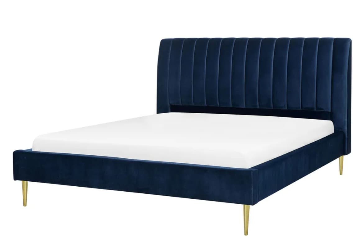 A modern platform bed featuring a tall, rectangular headboard with vertical channel tufting, and a low-profile bed frame, all upholstered in navy blue velvet. The bed is supported by four slender, tapered metal legs with a polished gold finish. A white mattress is visible within the frame. — 3D model