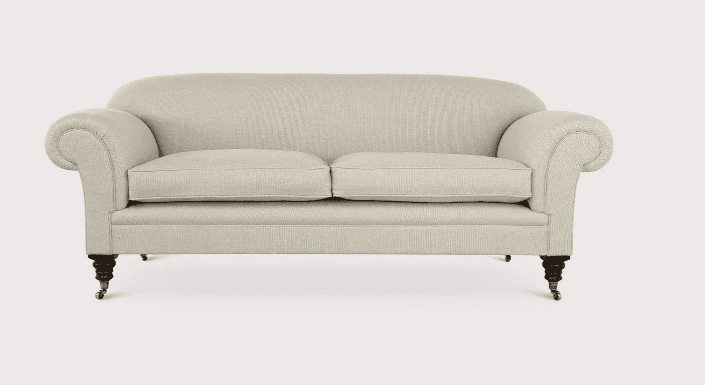 A light-colored, two-seater upholstered loveseat featuring classic rolled arms and two seat cushions. The piece rests on short, dark-stained turned wooden legs, each tipped with a brass caster for mobility. The upholstery is a textured, light beige or cream fabric, giving it a traditional or transitional aesthetic. The back is gently curved, and the overall form is compact. — 3D model