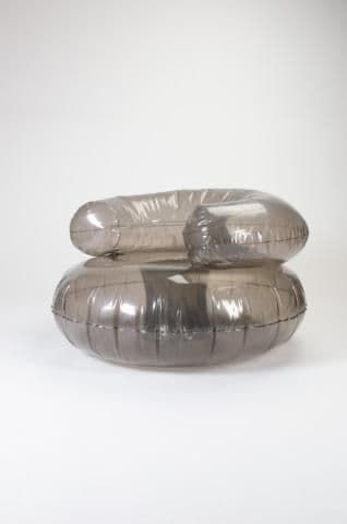 An armchair constructed from inflatable, translucent gray material. The design features a rounded, seat-like base and a backrest with integrated armrests, all formed from inflated sections. The overall shape is amorphous and somewhat futuristic. — 3D model