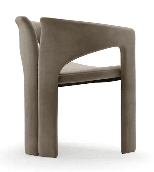 A contemporary armchair featuring a fully upholstered form in a neutral taupe or greige velvet-like fabric. The design incorporates a distinctive U-shaped armrest that flows into the front legs, paired with a separate, slightly curved backrest that extends downwards to form the rear legs. The entire structure is seamless and upholstered, giving it a plush, monolithic appearance. — 3D model