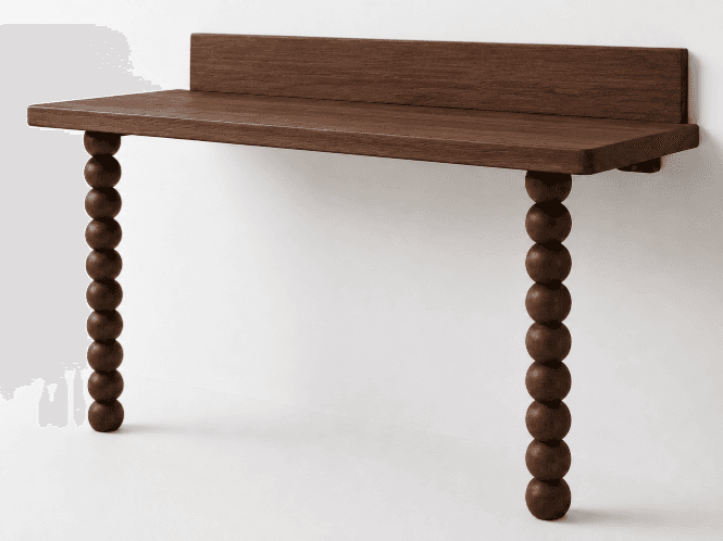 A contemporary console desk featuring a rectangular dark wood tabletop with an integrated backsplash and two distinctive bobbin-turned legs. The desk is designed for wall-mounting, creating a minimalist and floating aesthetic. — 3D model