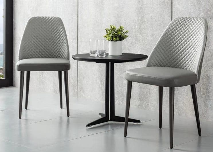 A modern black round side table with a minimalist design, featuring a circular top and a sturdy metal base with four legs connected by stretchers, rendered against a white background. — 3D model