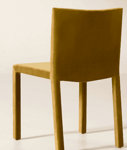 A contemporary dining chair fully upholstered in a mustard yellow velvet-like fabric. The chair features a minimalist design with a slightly curved backrest and straight, upholstered legs. The monochromatic finish gives it a sleek and modern appearance. — 3D model