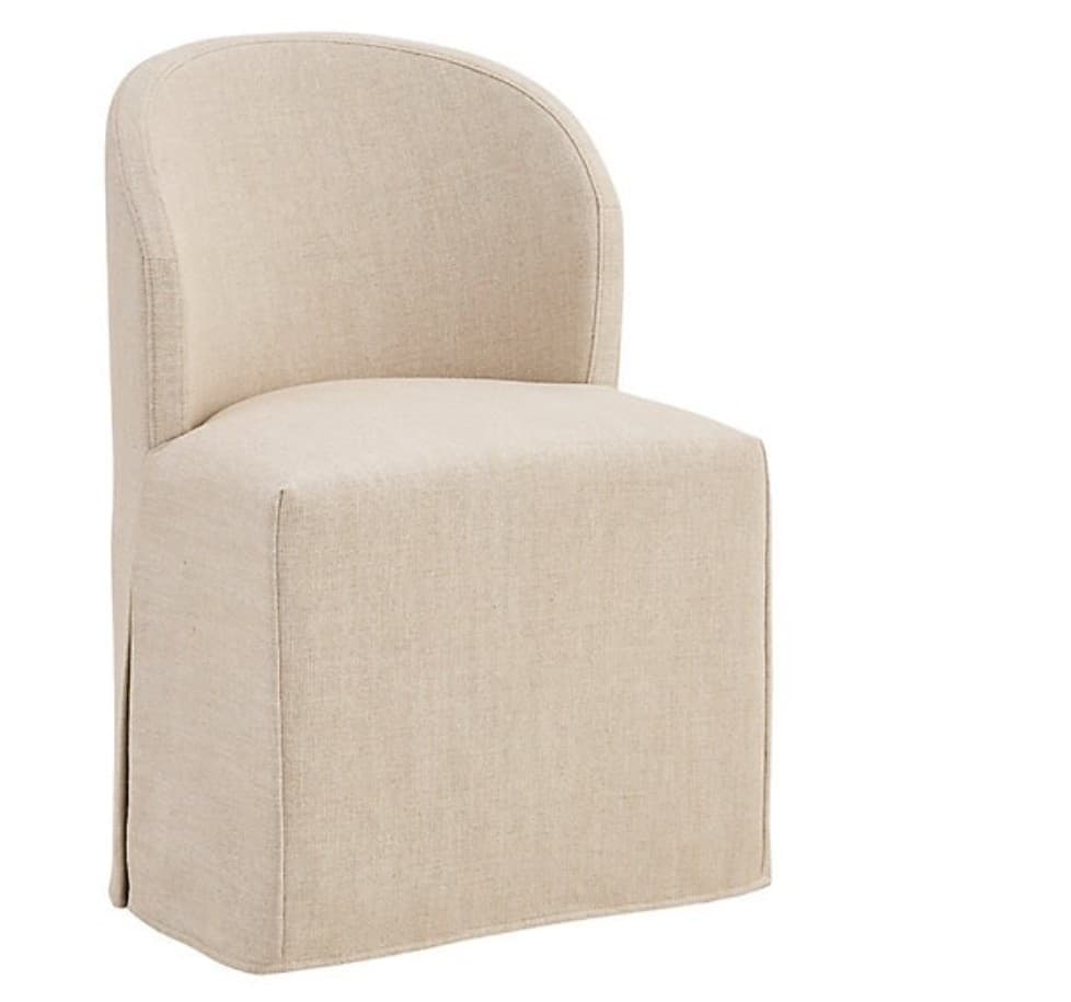A fully upholstered chair featuring a rounded, continuous barrel backrest and integrated armrests, covered entirely in a light beige, textured fabric. The chair's base is concealed by a tailored skirt that extends to the floor. — 3D model