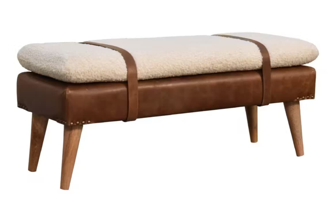 A rectangular bench with a brown leather upholstered base and a fluffy white cushion on top. The cushion is secured by brown leather straps that wrap around the bench. The base is adorned with decorative nailhead trim along its edges. It is supported by four tapered wooden legs. — 3D model
