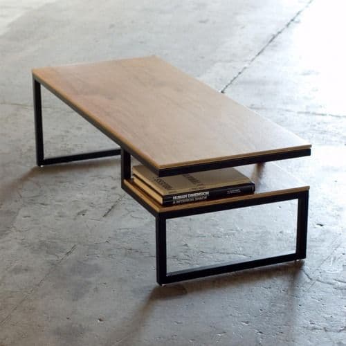 A rectangular, two-tier coffee table featuring light-colored wooden surfaces and a black metal frame. The top tier is significantly larger and is offset from the smaller, lower tier, creating a dynamic, multi-level design. The frame consists of minimalist rectangular metal tubing, providing a sturdy, open base. — 3D model