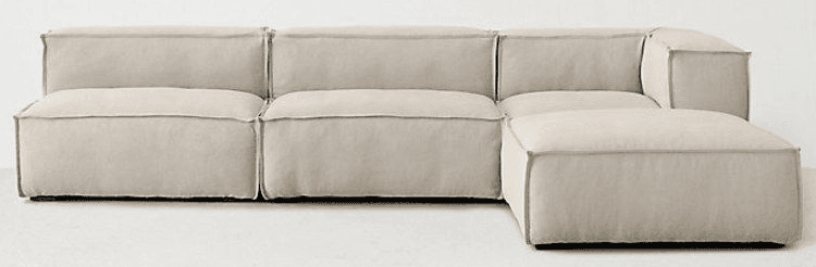 A modular sectional sofa with clean lines and a low profile. It features plush, oversized cushions and is upholstered in a light-colored fabric. The construction appears to be fabric-covered, with visible stitching along the edges. — 3D model
