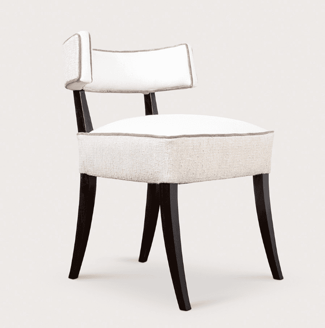 An upholstered armless side chair featuring a padded seat and a low, curved backrest. The upholstery is a light, possibly linen-blend fabric with contrasting darker piping along the edges of both the seat and the back. The chair is supported by four dark-stained, tapered wood legs that splay slightly outward. The overall design suggests a contemporary or modern classic aesthetic. — 3D model