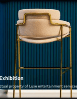 A modern bar stool featuring a padded upholstered seat and a curved backrest, supported by a slender gold-finished metal frame. It includes a black footrest bar for comfort. — 3D model