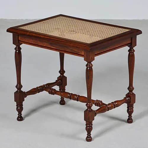 A rectangular accent table constructed from dark brown turned wood with a woven cane top. It features decorative turned legs connected by X-shaped stretcher bars near the base, terminating in ball feet. — 3D model