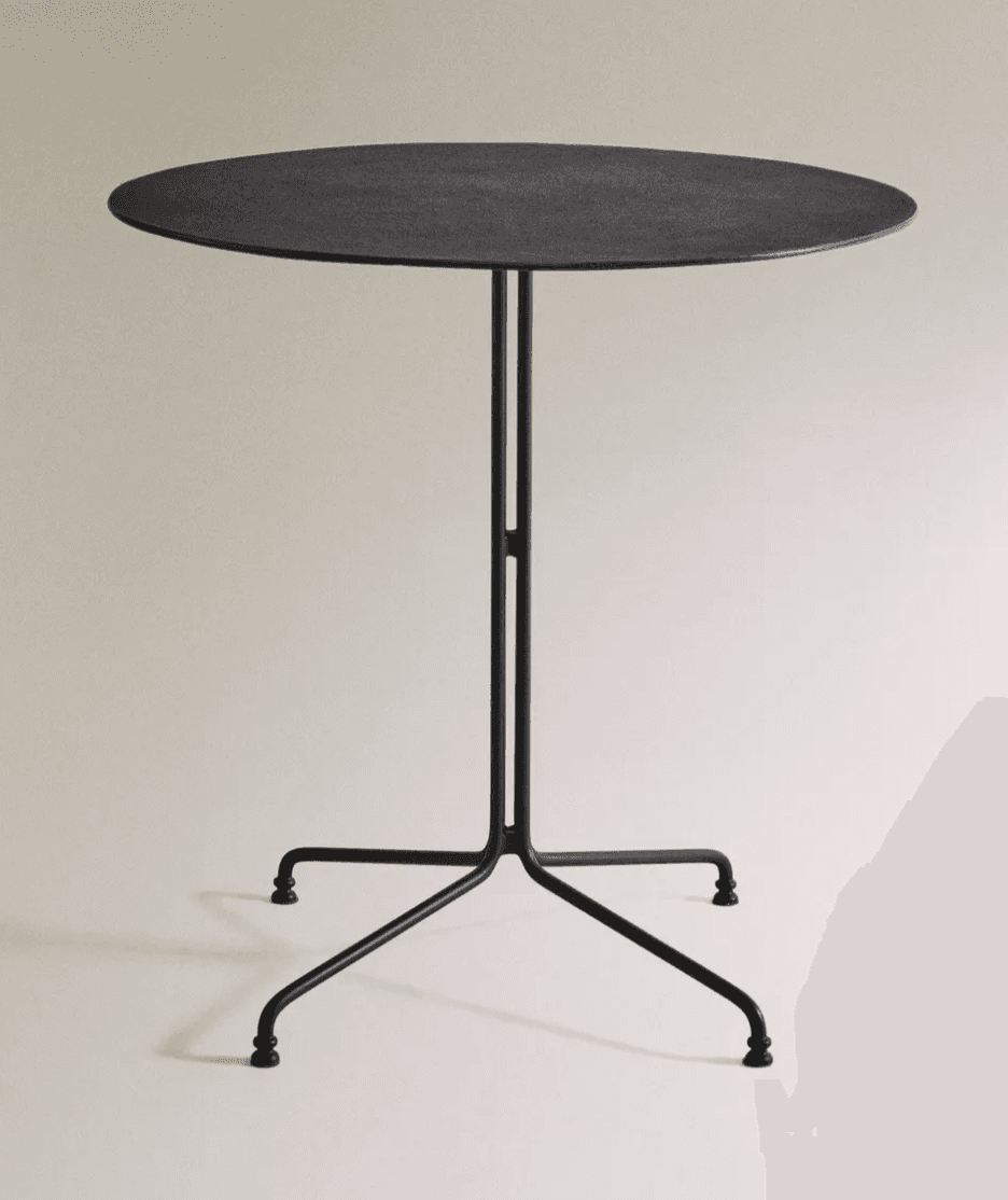 A minimalist side table with a round, flat top and a slender, dark-colored pedestal base. The base has a three-pronged, spread-leg design that tapers down to small, rounded feet. The central column of the base is thin and straight, with a subtle horizontal accent approximately midway up. The tabletop has a slightly textured surface. — 3D model
