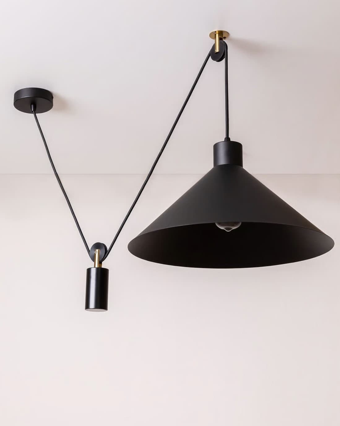 A black conical pendant light featuring an adjustable suspension system with brass-accented pulleys and a cylindrical counterweight, designed for flexible height adjustment. — 3D model