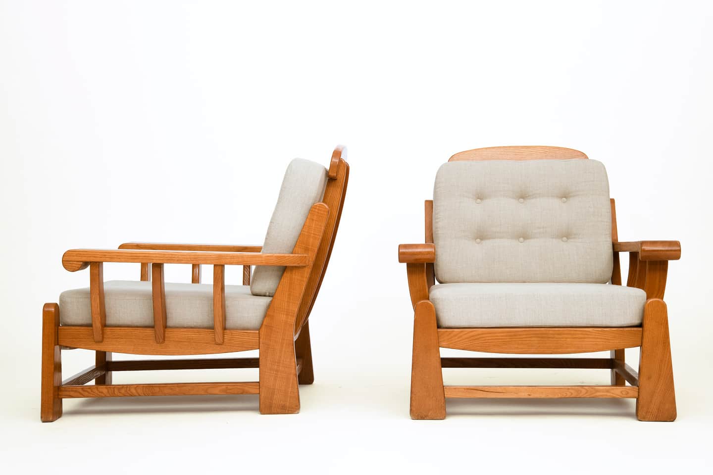 A pair of lounge chairs, each featuring a robust wooden frame with light-colored upholstered seat an… — 3D model