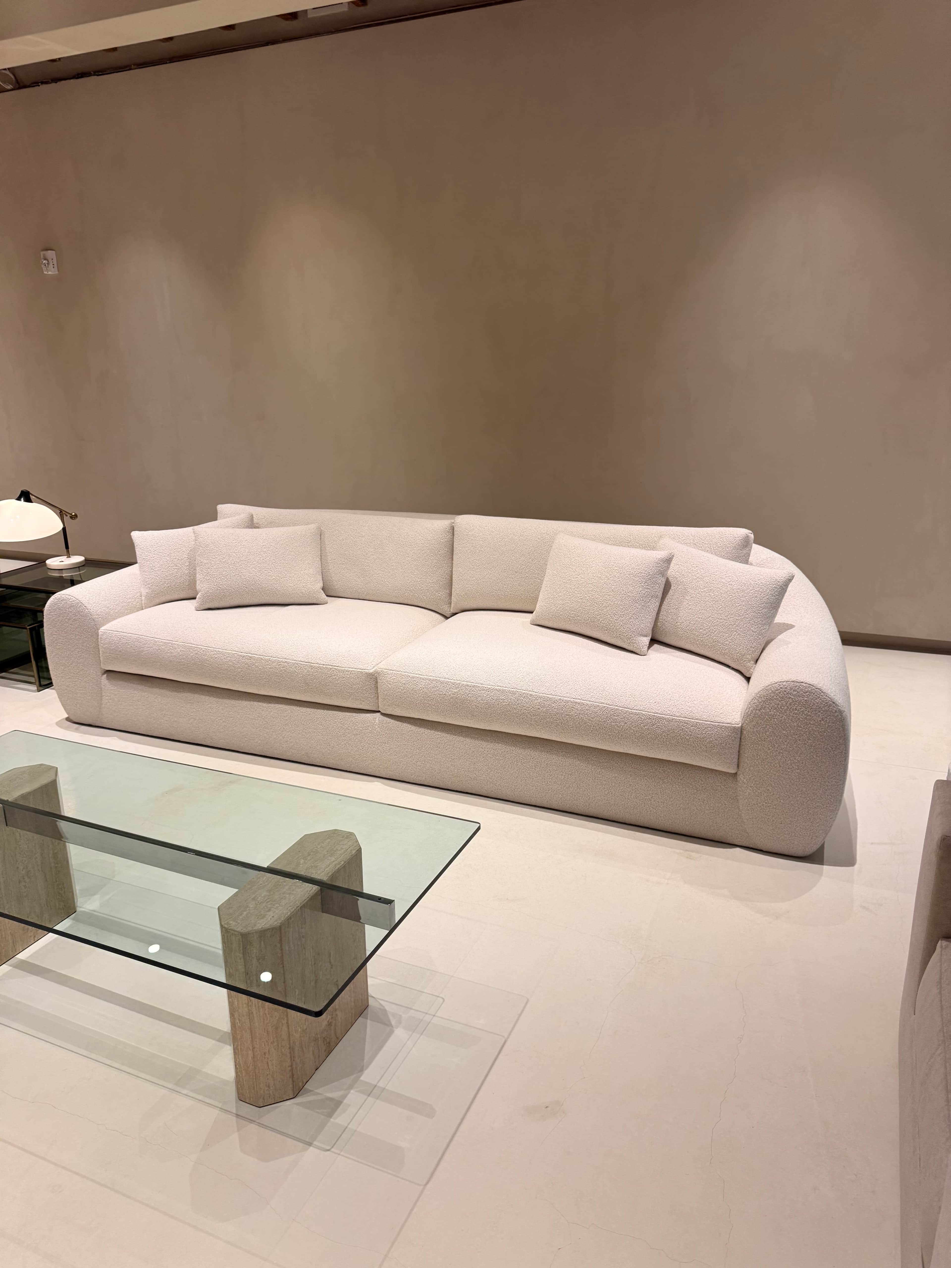 A long, contemporary upholstered sofa featuring a light cream fabric, soft rounded armrests, and a l… — 3D model