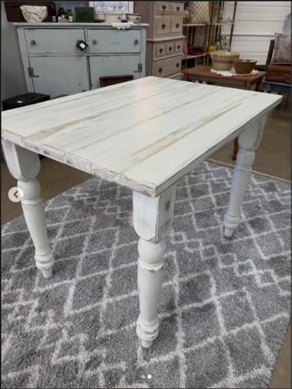 A rectangular, distressed white wooden accent table with four turned legs, presented against a clean white background. The finish shows intentional signs of wear, revealing hints of the natural wood underneath. — 3D model