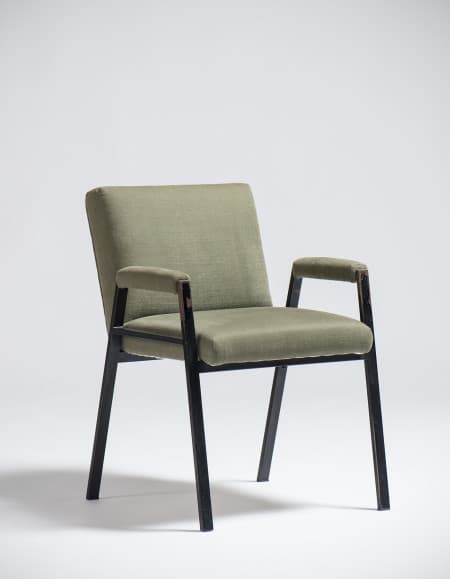 An armchair with a dark-colored frame and upholstered seat, back, and armrests in a light olive green fabric. The frame appears to be made of metal or a dark wood, with slender legs and arm supports. The upholstery has a textured weave. The design suggests a mid-century modern or contemporary aesthetic. — 3D model