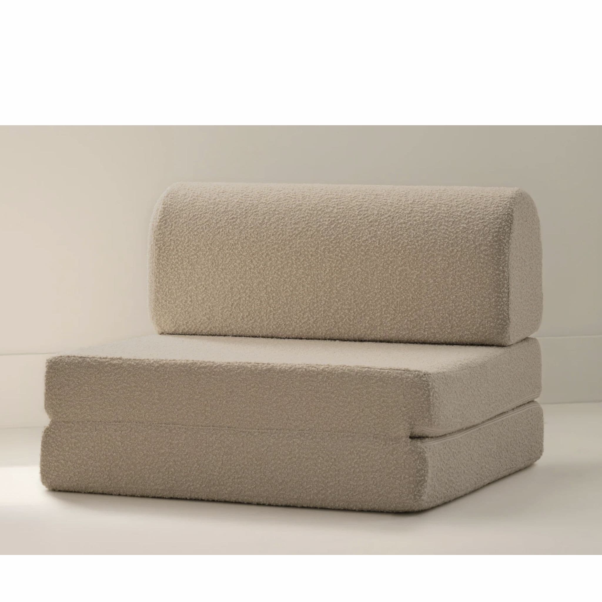 A neutral-toned, beige modular foam chair, constructed from multiple foldable sections, upholstered in a textured fabric. The item is configured as a low-profile chair with a distinct rounded cylindrical backrest positioned atop two stacked, rectangular base sections. — 3D model