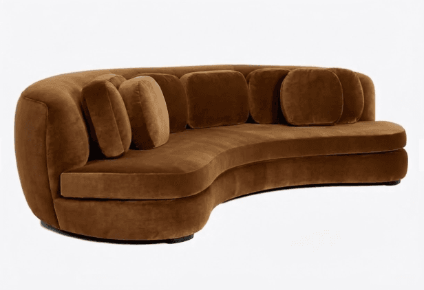 A curved sofa with a plush velvet upholstery. The sofa features a rounded silhouette and is adorned with several throw pillows, some of which are square and others are rounded. The armrests are integrated into the curved design. — 3D model