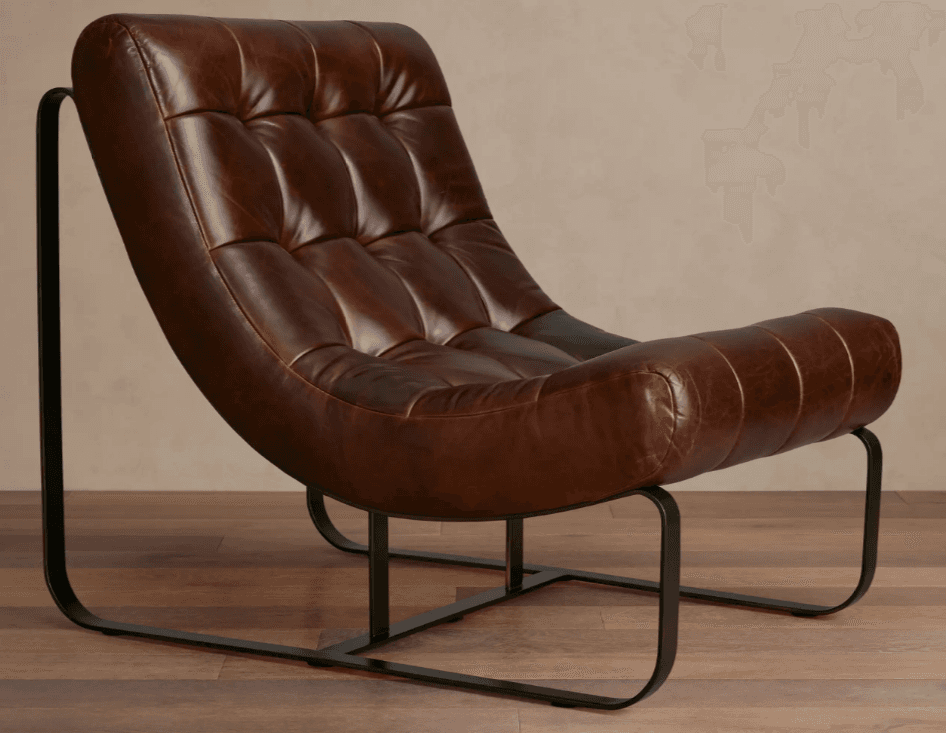 A low-profile lounge chair with a curved, tufted seat and back, upholstered in distressed brown leather. The frame is constructed from thin, black metal tubing, forming a sled-base design that provides stability. The seat features deep channel tufting for a plush appearance. The armrests are integrated into the main body of the seat, with a slightly raised edge. — 3D model