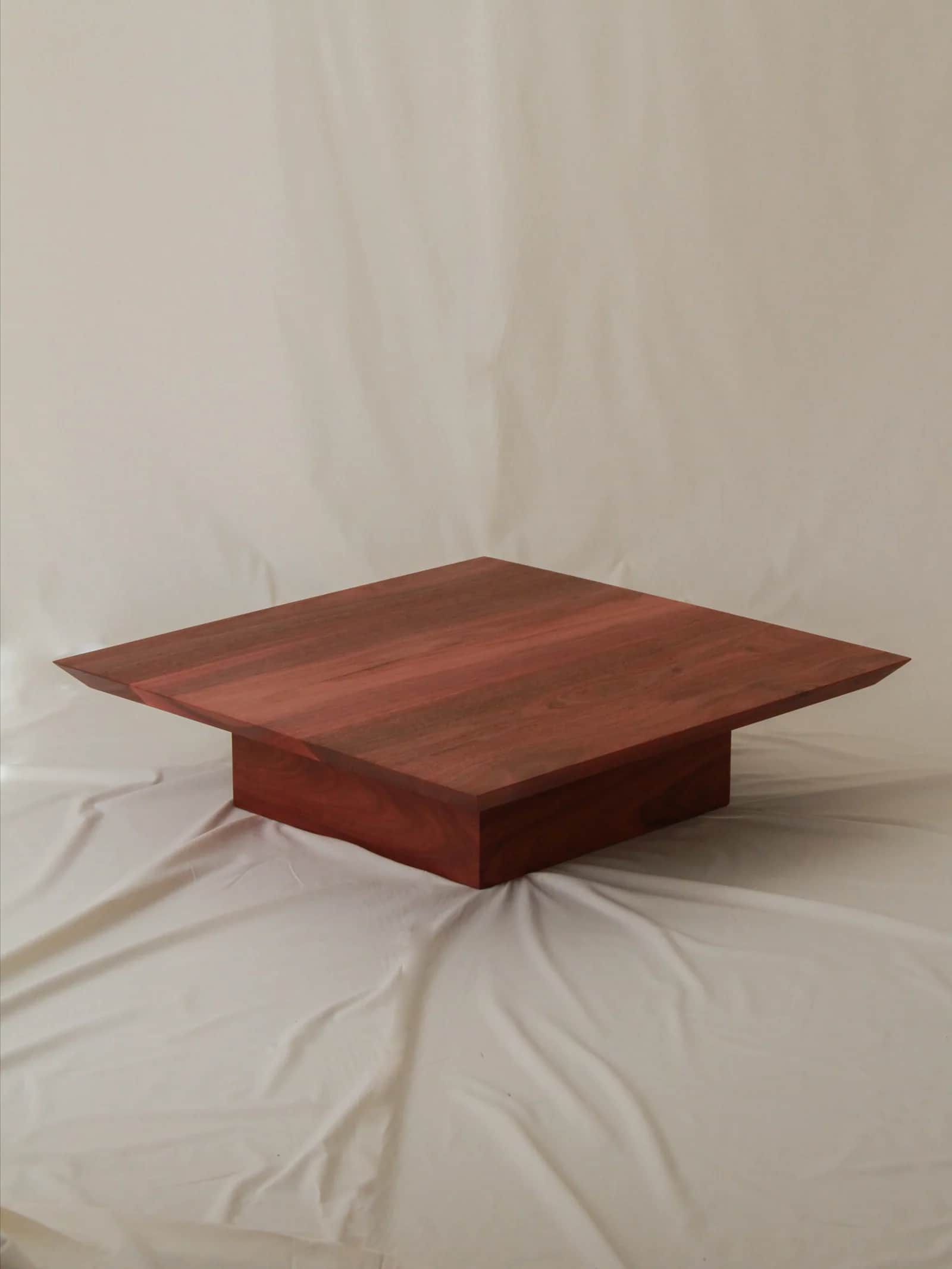 A modern, square-shaped coffee table crafted from reddish-brown wood, featuring a thick tabletop tha… — 3D model