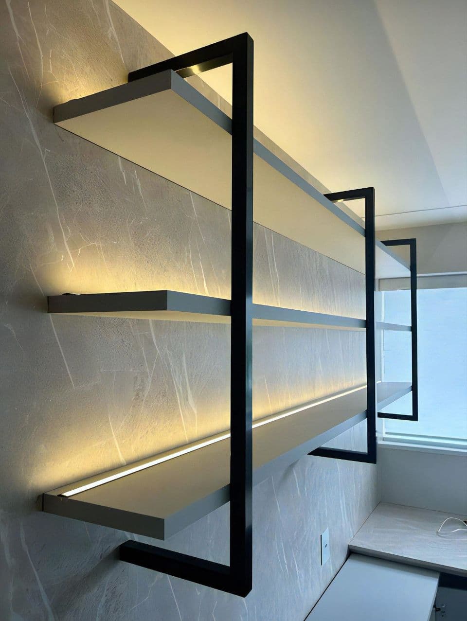 A contemporary four-tiered wall-mounted shelving unit featuring light gray shelves and a matte black metal frame. Each shelf has an integrated LED light strip on its underside, designed to illuminate the shelf below. — 3D model