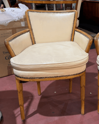 An elegant upholstered armchair featuring a barrel back design, exposed wooden frame with nailhead trim, and fluted tapered legs. The upholstery is a light cream or beige color, contrasting with the light-toned wood. — 3D model