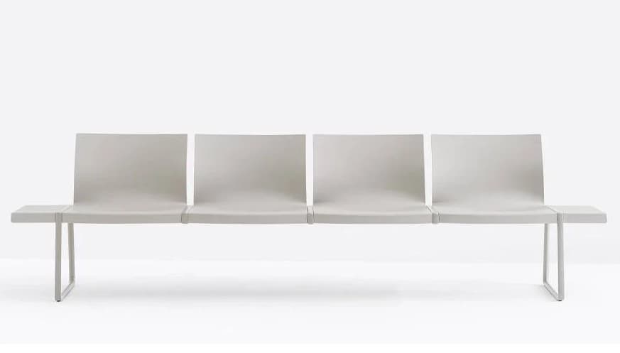 A long, grey, multi-seat bench designed for public waiting areas, featuring four individual seating units with slightly curved backrests and flat seats, flanked by integrated flat side tables. The entire structure is supported by minimalist U-shaped metal legs. — 3D model