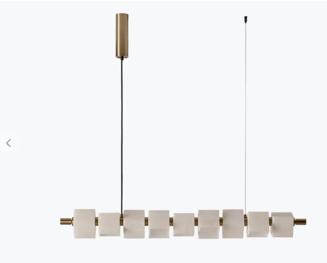 A modern linear pendant light fixture featuring a horizontal bar adorned with multiple rectangular translucent diffusers, suspended by thin wires from a brass-toned canopy. The overall design is minimalist and contemporary. — 3D model