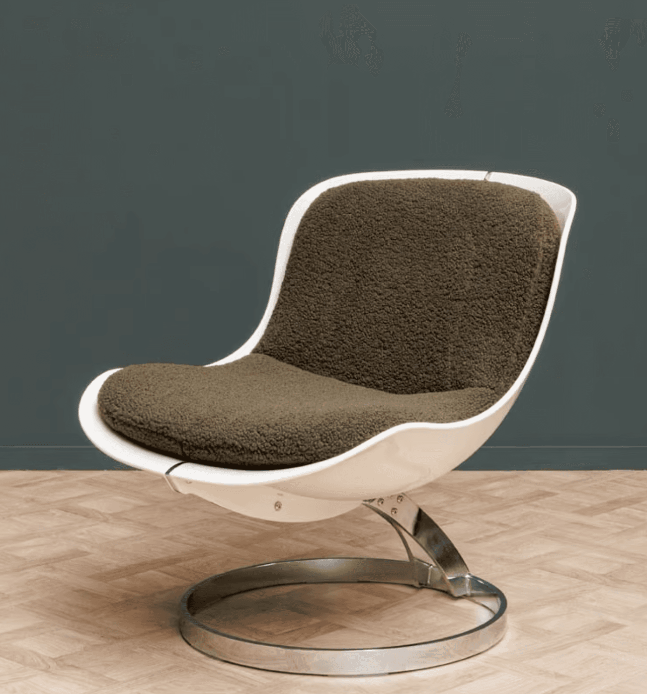 A modern armchair featuring a white molded shell seat and back, with a thick, textured green cushion. The chair is supported by a chrome-plated metal base with a circular pedestal and a curved upright structure connecting to the seat. — 3D model