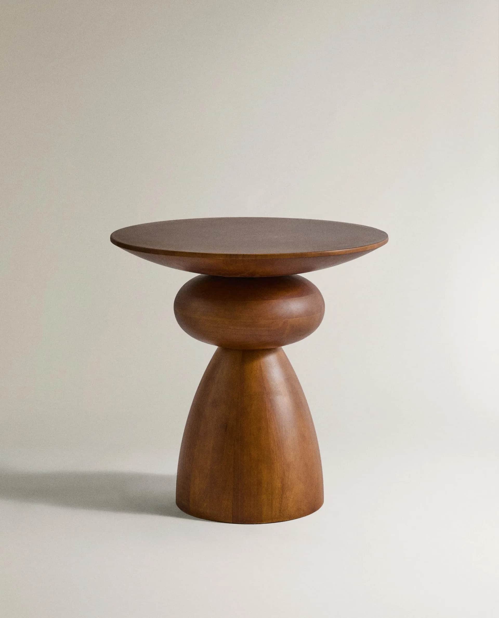A sculptural accent table crafted from solid wood, featuring a round, slightly dished top supported… — 3D model