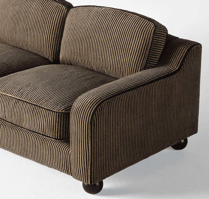 A close-up view of a sofa with a striped upholstery fabric. The sofa features plump cushions, rounded armrests, and short, spherical black legs. The fabric has a ribbed texture with vertical stripes in alternating shades of gold and black. — 3D model