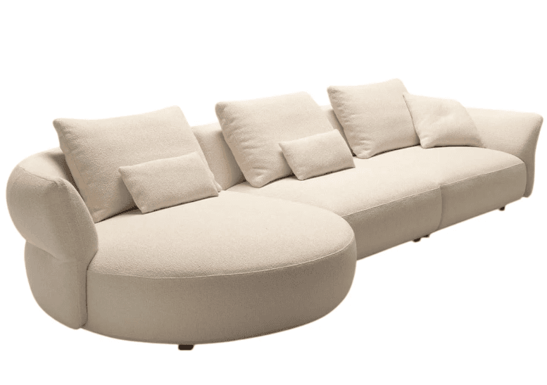 An L-shaped sectional sofa upholstered in a light cream bouclé fabric. The design features soft, rounded contours, particularly noticeable on the armrests and the curvilinear chaise lounge extension. It includes multiple loose back cushions and smaller lumbar pillows, all covered in the same textured fabric, contributing to a plush and inviting appearance. — 3D model