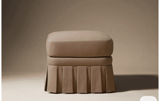 A square, upholstered ottoman featuring a plush top cushion and a continuous box-pleated fabric skir… — 3D model