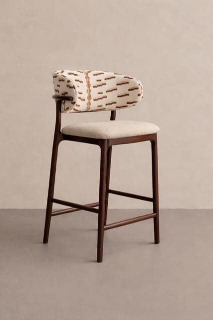 A bar stool featuring a dark wood frame with a light-colored upholstered seat and a distinctively patterned upholstered backrest. The backrest is curved and partially wraps around, offering slight arm support. The legs are slender, joined by footrests and cross-bracing for stability. — 3D model