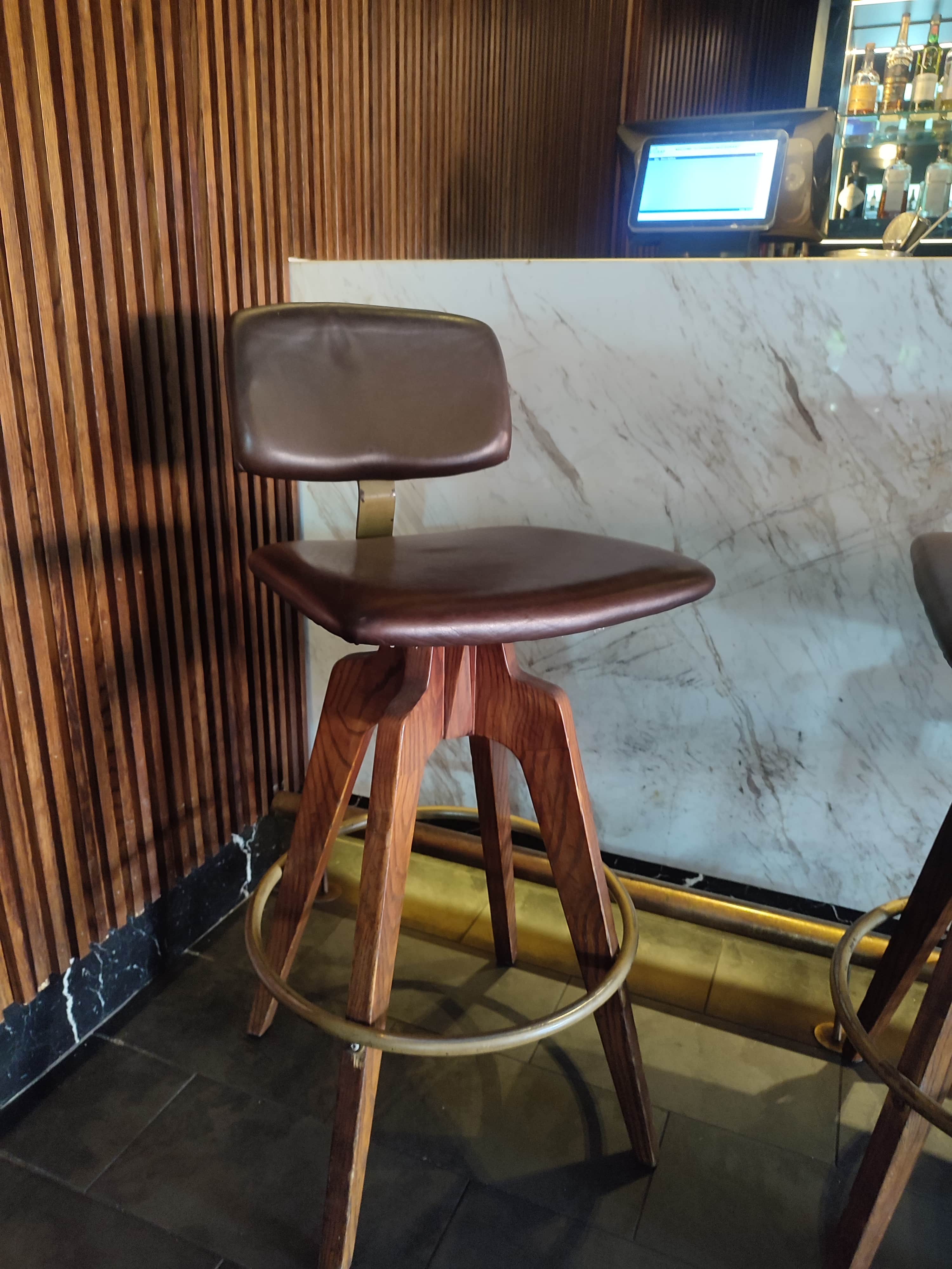 A brown bar stool with a swiveling seat and backrest, supported by a wooden tripod base. The seat an… — 3D model