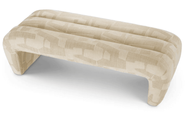A low-profile, upholstered ottoman with a rounded rectangular form and curved, integrated legs. The top surface features three distinct, padded horizontal channels. The upholstery is a woven fabric with an abstract, geometric pattern in contrasting shades of beige and cream. — 3D model