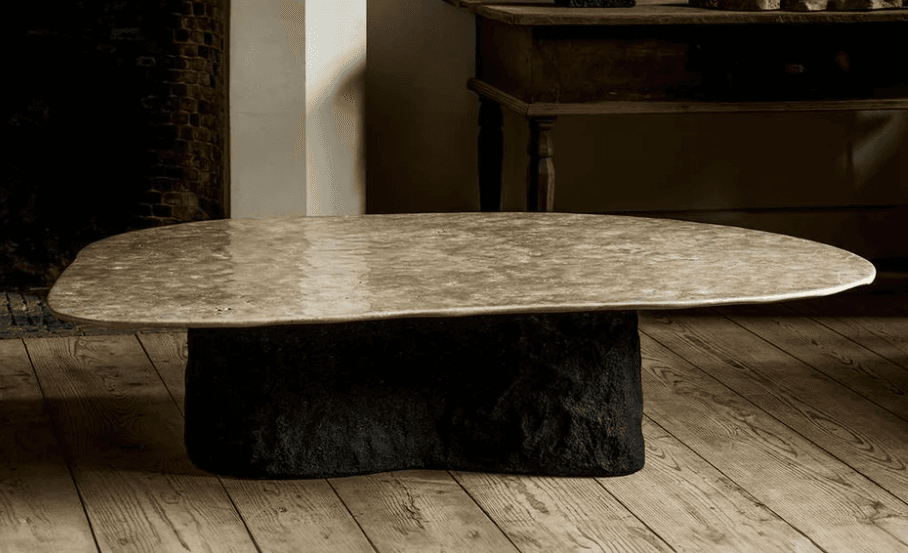 A low-profile coffee table featuring an organically shaped, light-colored natural stone top resting upon a dark, heavily textured, monolithic stone base. The irregular contours and contrasting materials give it a sculptural aesthetic. — 3D model