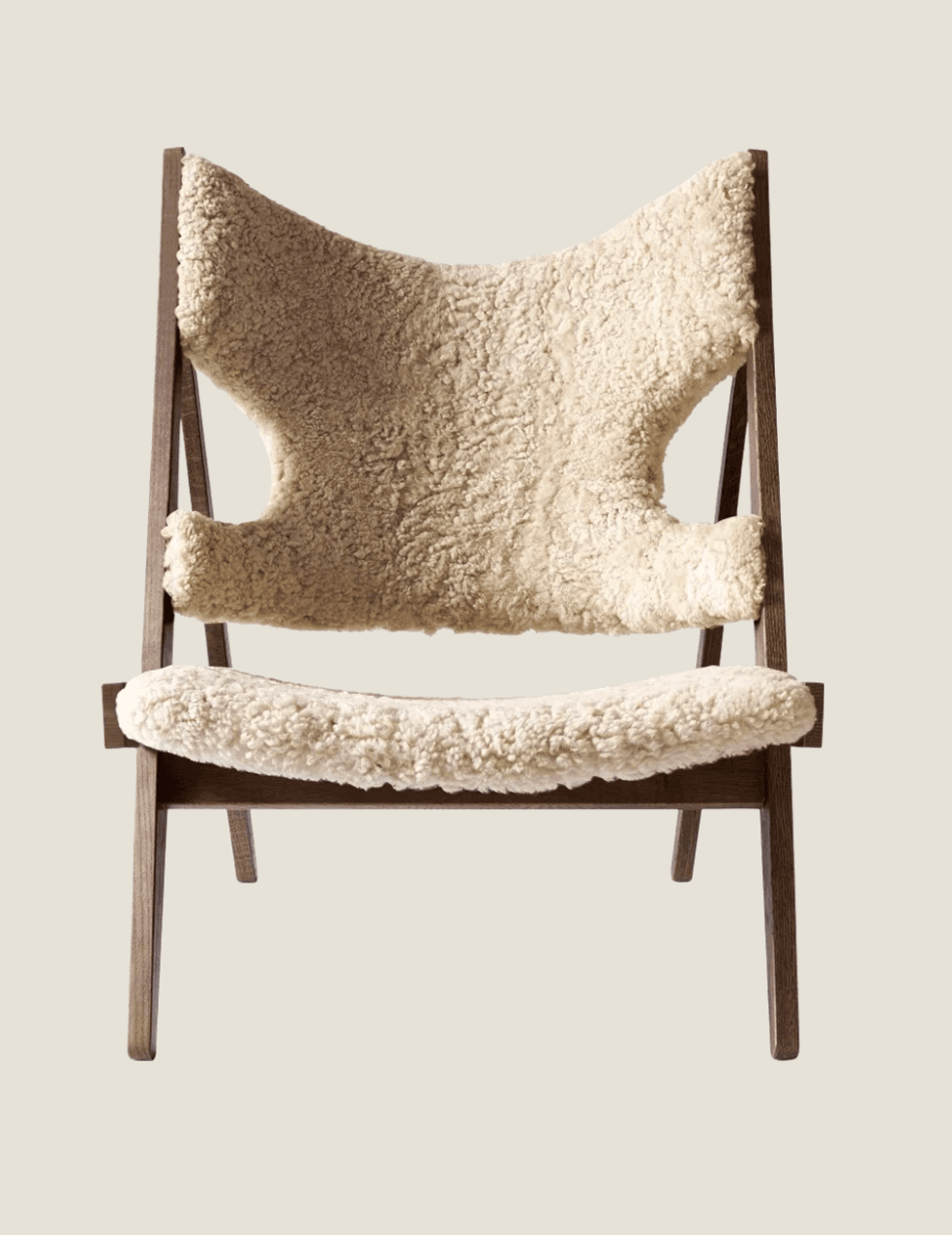 A contemporary lounge chair featuring a dark-stained wooden A-frame style base and a plush, cream-colored sheepskin upholstery for both the seat and backrest. The design is characterized by its relaxed posture and organic materials. — 3D model