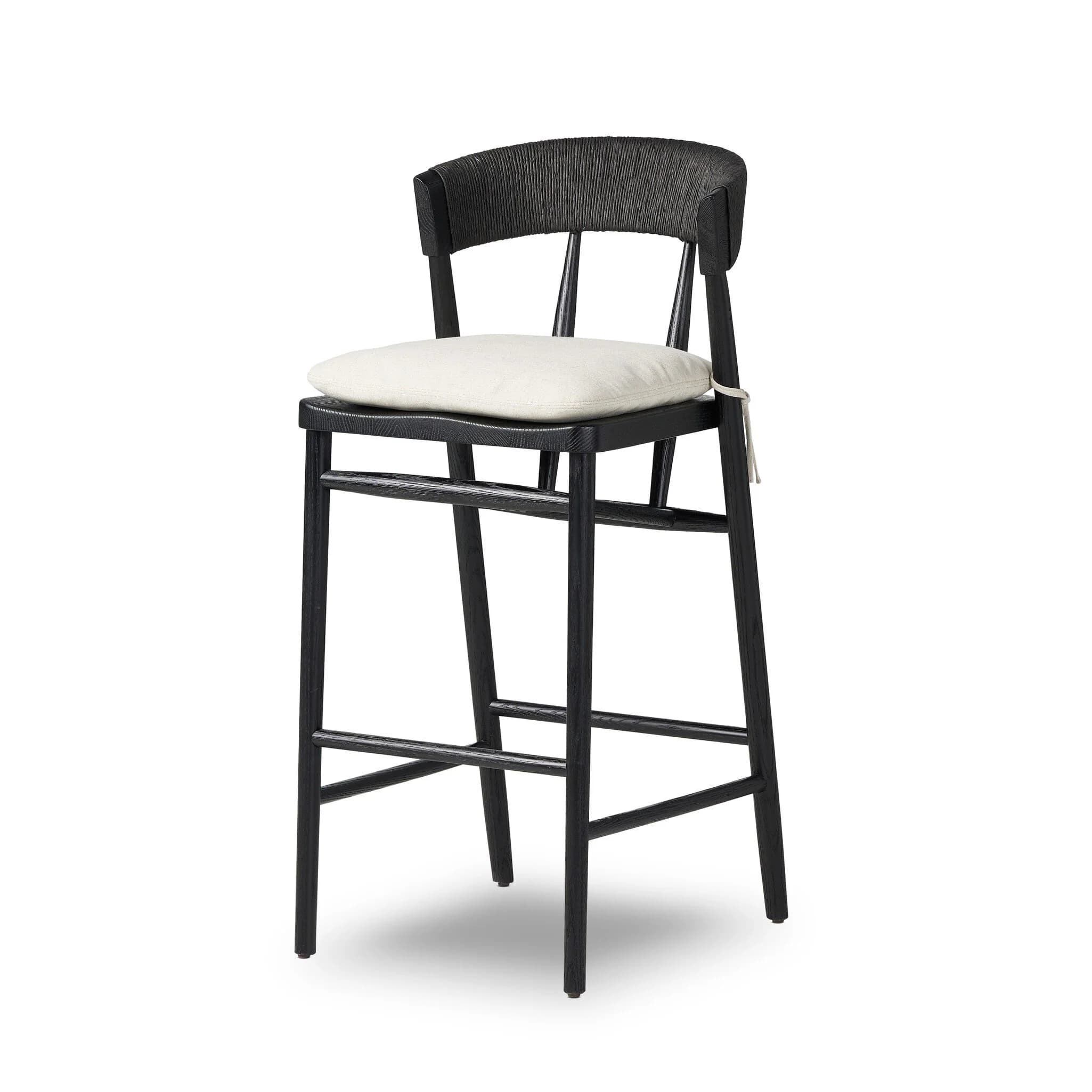 A modern bar stool with a black wooden frame and a woven backrest. It features a lightly upholstered, square seat cushion in a neutral tone. The stool has four legs connected by crossbars for stability. A white string is tied to one of the front legs. — 3D model