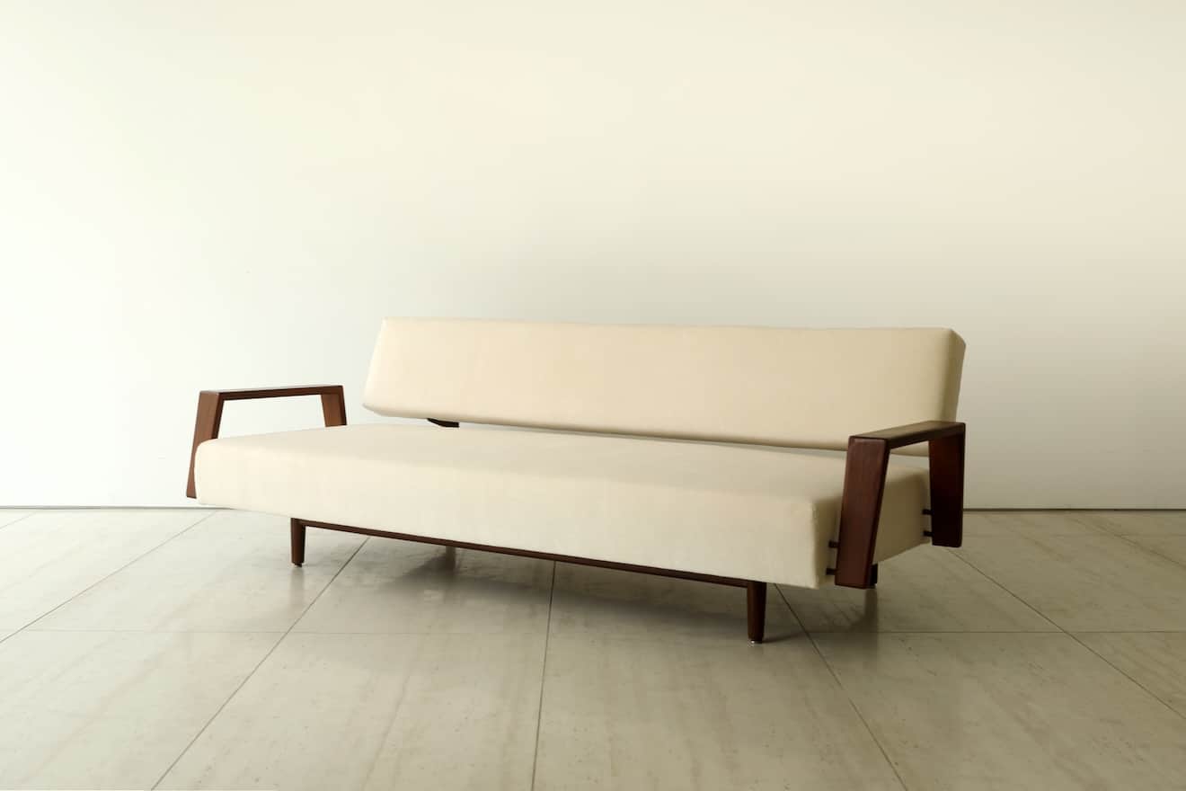 A minimalist two-seater loveseat featuring a cream-colored upholstered seat and backrest, supported… — 3D model