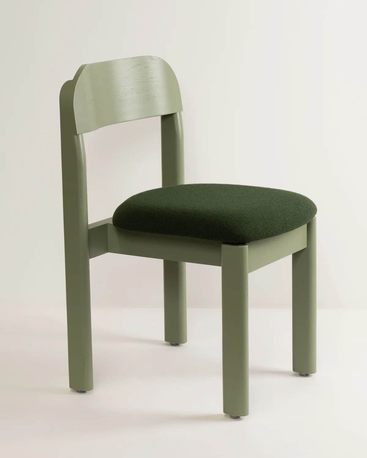 A modern dining chair featuring a sage green wooden frame with cylindrical legs and a gently curved… — 3D model