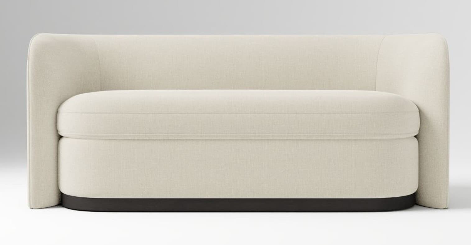 An upholstered loveseat with a modern, low-profile design. It features cream-colored fabric upholstery, a single seat cushion with piping, and integrated rounded arms and back. The entire piece rests on a dark, recessed base, creating a floating effect. — 3D model