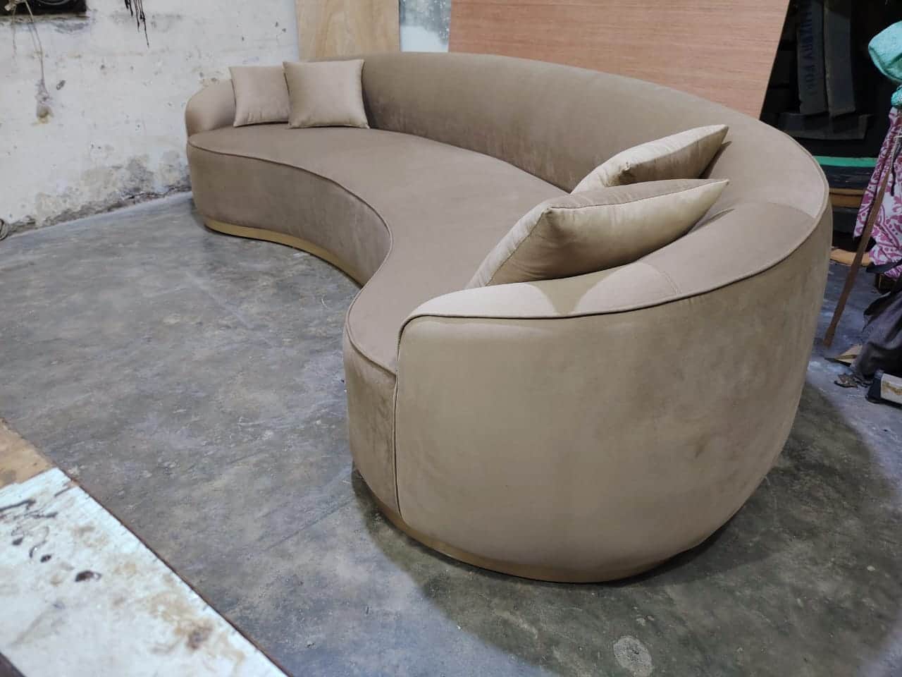 A modern, curvilinear sofa upholstered in a light beige or taupe fabric, featuring a low, continuous… — 3D model