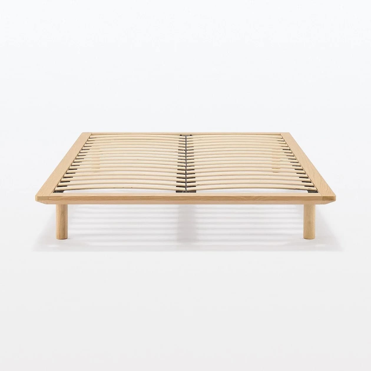 A light-colored wooden bed frame featuring a slatted base for mattress support and four sturdy, cylindrical legs, designed for a minimalist aesthetic. — 3D model