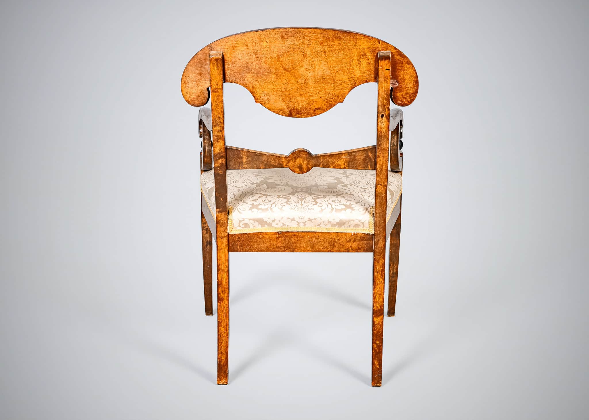 An antique armchair featuring a distinctive curved and carved backrest, likely made from curly maple… — 3D model