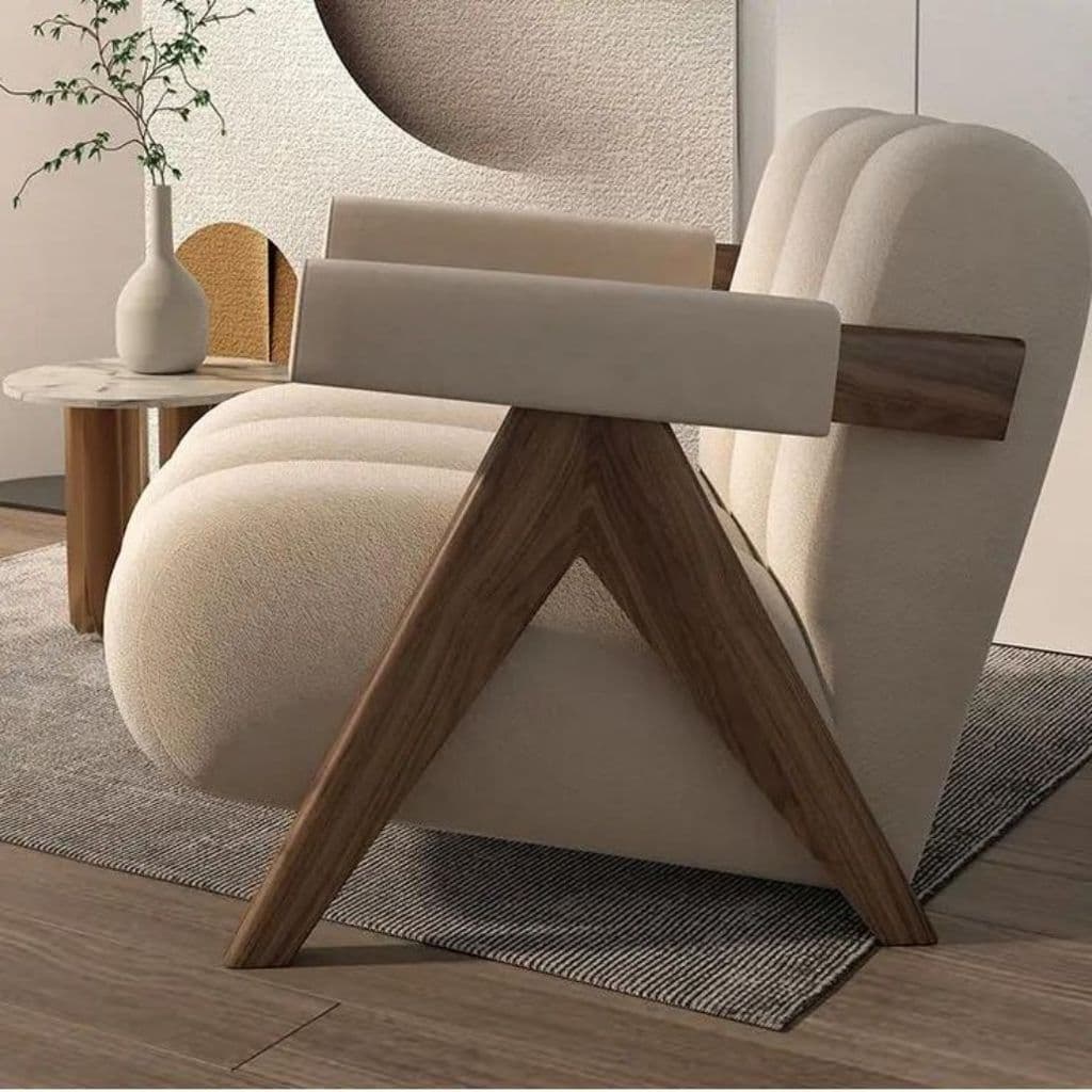 A contemporary armchair featuring deeply fluted cream-colored upholstery and an exposed, angular dark wood frame. The chair has a plush, rounded appearance with vertical channels forming the backrest and seat. The armrests are padded and covered in matching upholstery, supported by the striking V-shaped wooden frame components that also form the legs. — 3D model