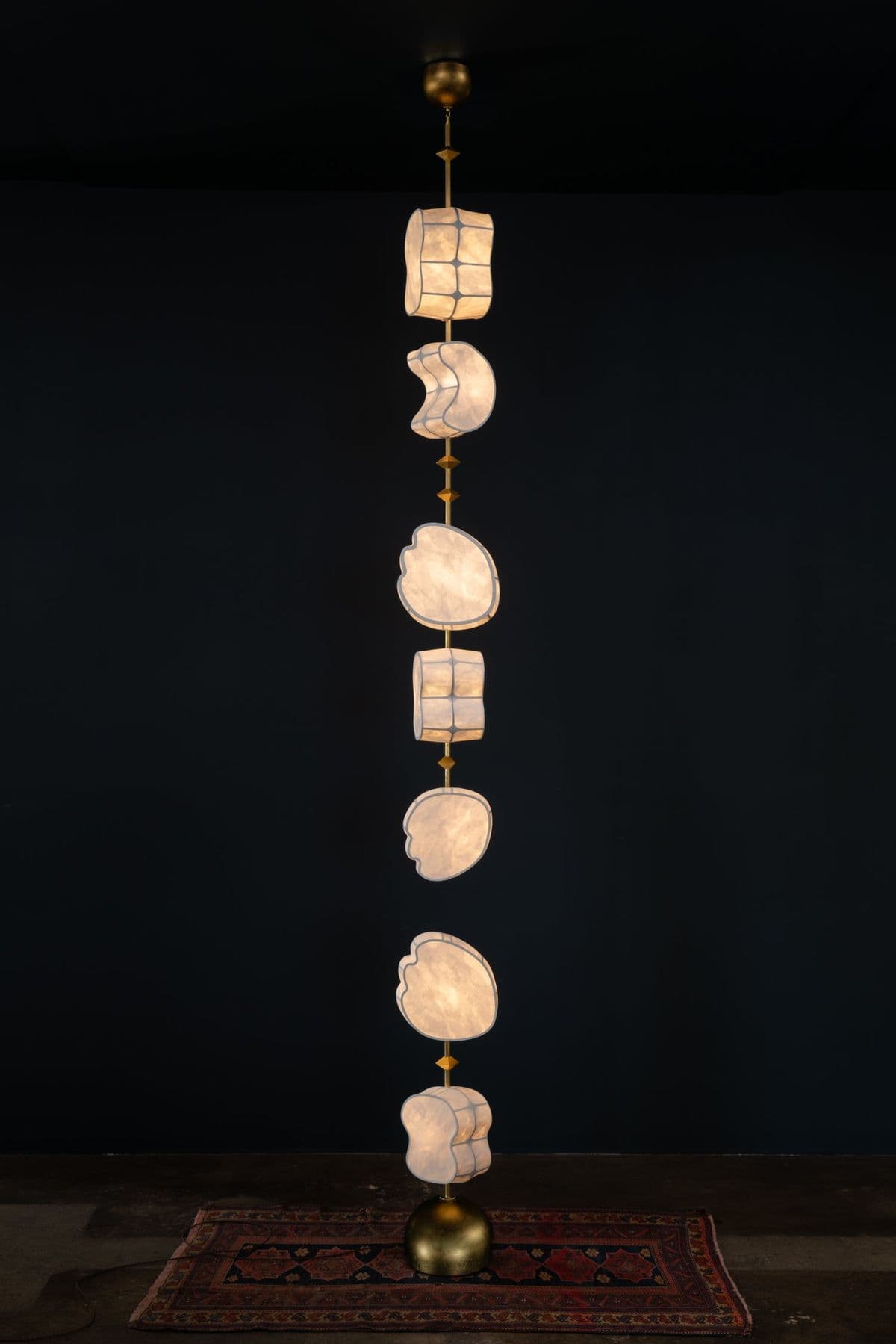 A tall, vertically oriented chandelier featuring multiple tiers of irregularly shaped diffusers made of a translucent material, interspersed with metallic elements, all suspended from a central rod. — 3D model