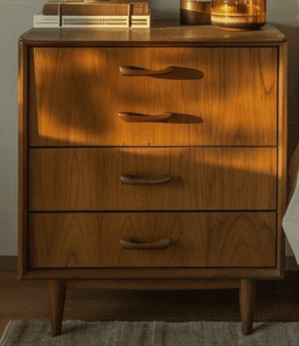 A light-toned wooden nightstand featuring three drawers, rounded edges, integrated carved pulls, and… — 3D model